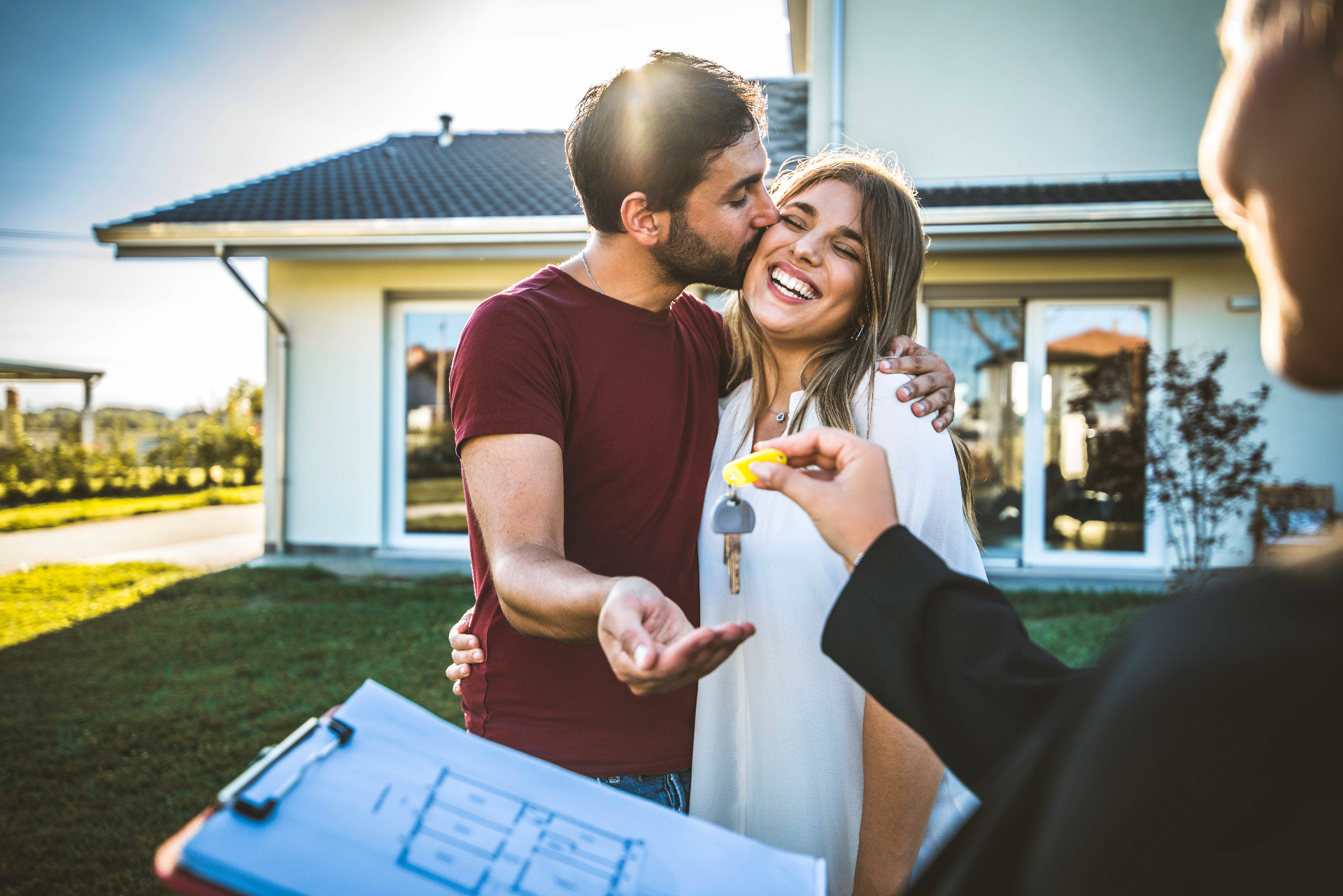 A young couple celebrating receiving the keys to their new home from their real estate agent